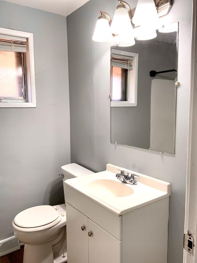 half bath with vanity, toilet, and visible vents