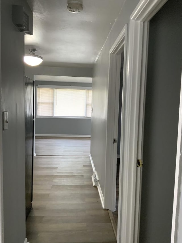 corridor featuring baseboards and wood finished floors