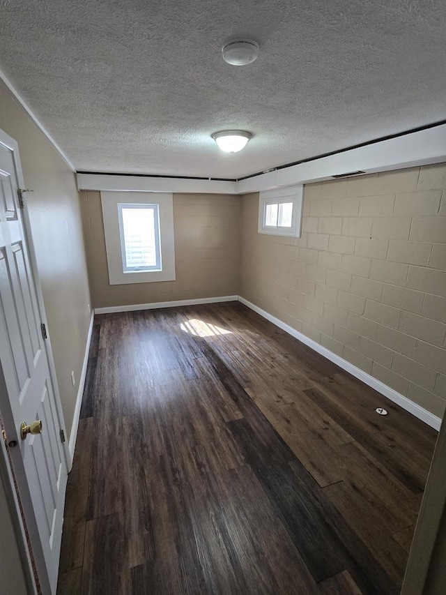unfurnished bedroom featuring baseboards, multiple windows, dark wood-style floors, and a textured ceiling