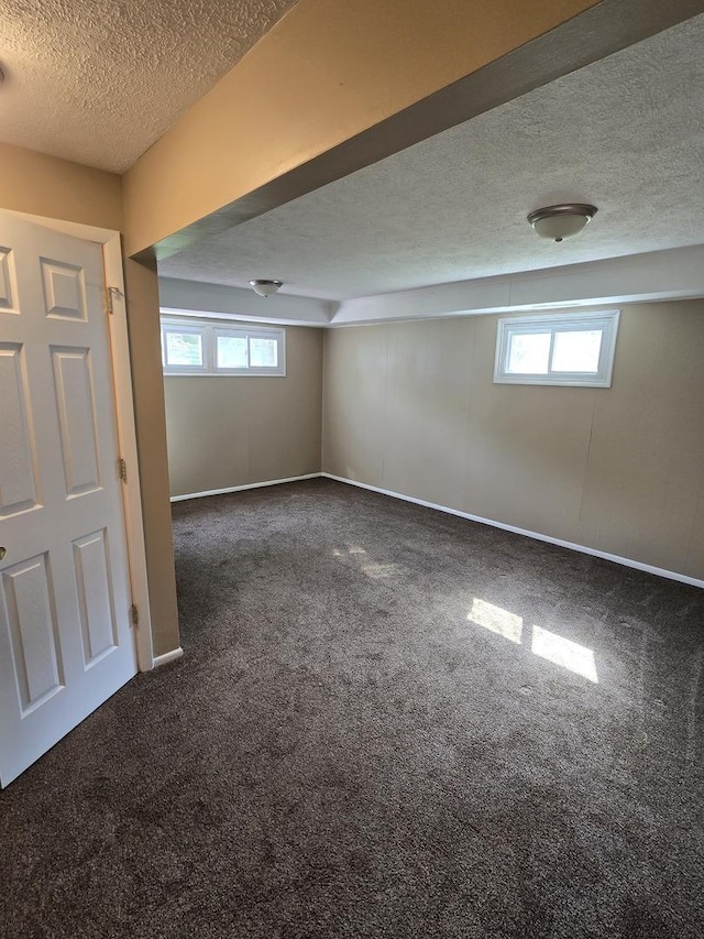 basement with baseboards, a textured ceiling, a healthy amount of sunlight, and carpet