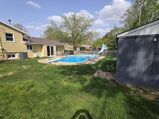view of pool with a water slide, a diving board, a yard, and central AC unit