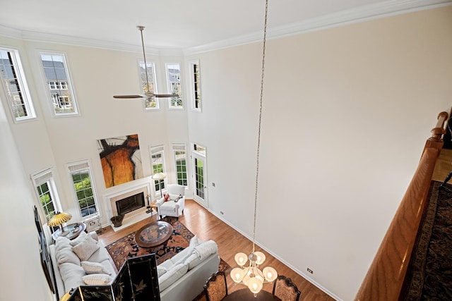 living area featuring a fireplace with flush hearth, ornamental molding, a wealth of natural light, and wood finished floors