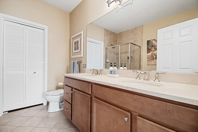 bathroom with a sink, tile patterned floors, a shower stall, and a closet