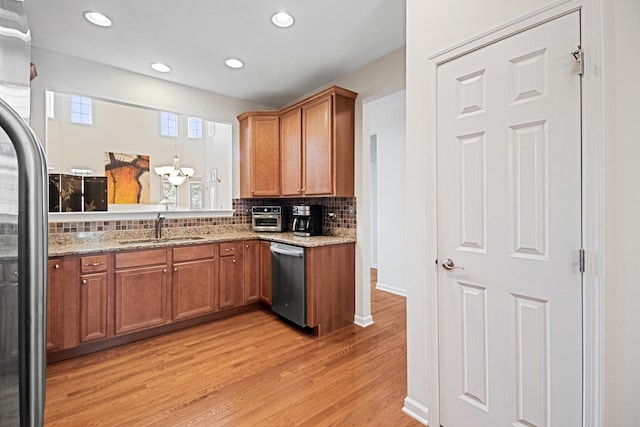kitchen featuring brown cabinets, stainless steel appliances, a sink, and light wood-type flooring