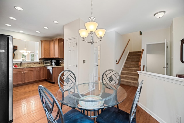 dining space with light wood-style floors, recessed lighting, stairs, and a notable chandelier