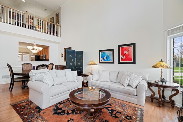 living area featuring a high ceiling, wood finished floors, and a chandelier