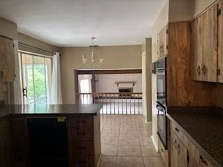 2700 Chariot Ln, Olympia Fields, IL 60461 - kitchen with dark countertops, a peninsula, a chandelier, light tile patterned floors, and hanging light fixtures