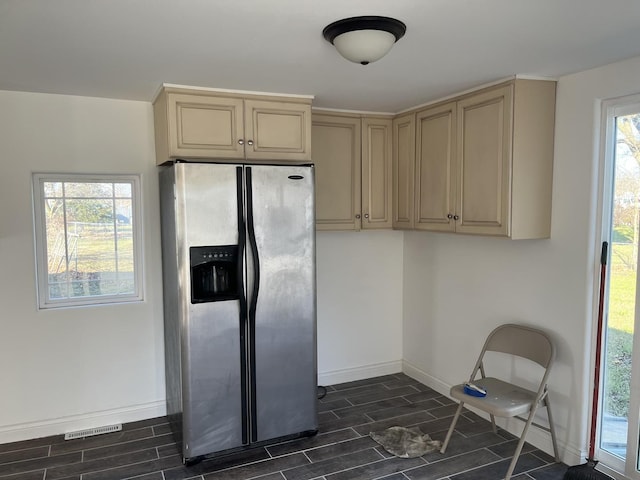 kitchen with baseboards, wood finish floors, cream cabinets, and stainless steel fridge with ice dispenser