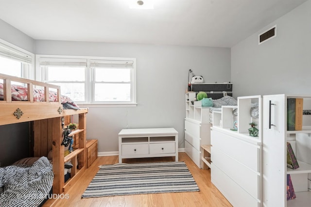 bedroom with visible vents, baseboards, wood finished floors, and multiple windows