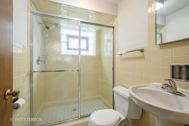 full bathroom with a sink, a stall shower, toilet, and tile walls