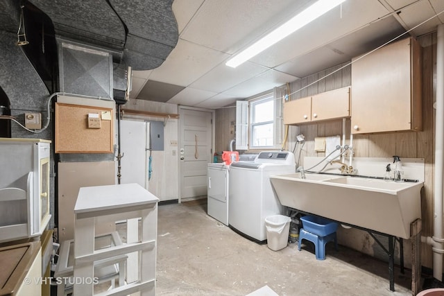 clothes washing area featuring independent washer and dryer, electric panel, and cabinet space