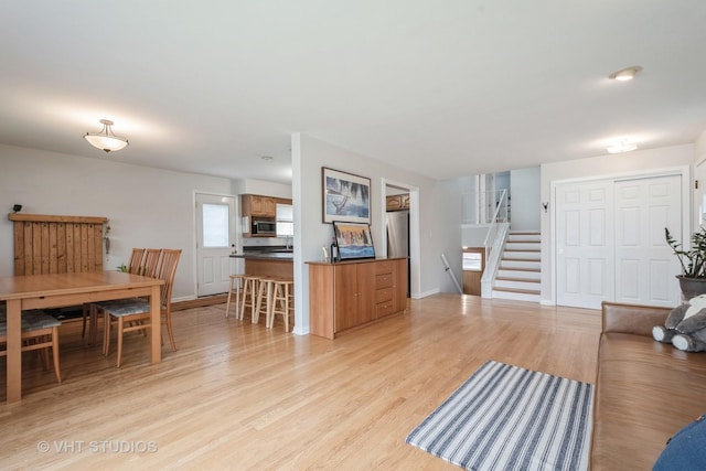 living area featuring stairs, baseboards, and light wood finished floors