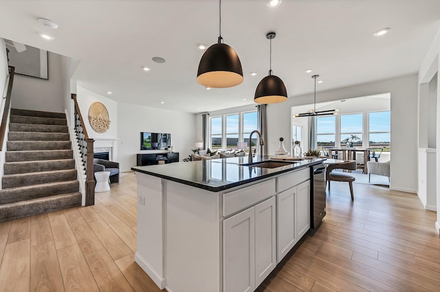 kitchen with a sink, light wood-style floors, stainless steel dishwasher, and a healthy amount of sunlight