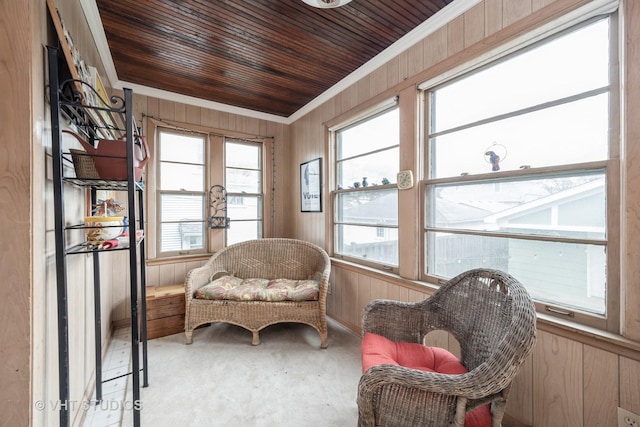 living area with crown molding, wood walls, wooden ceiling, and carpet