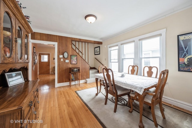 dining space with crown molding, stairs, light wood finished floors, and baseboards