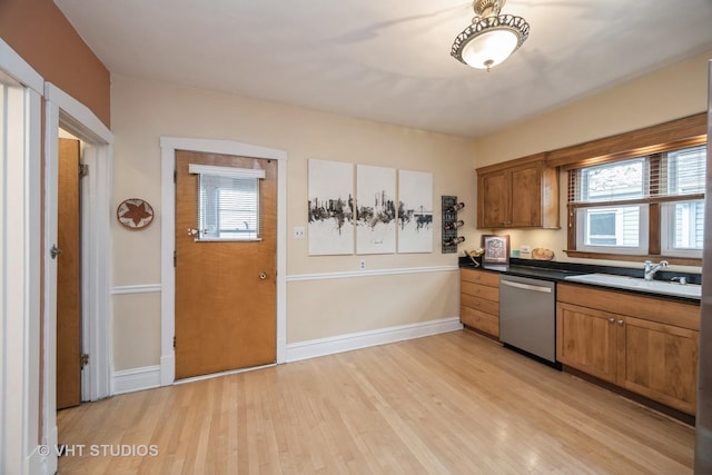 kitchen with a sink, brown cabinetry, stainless steel dishwasher, and light wood-style flooring
