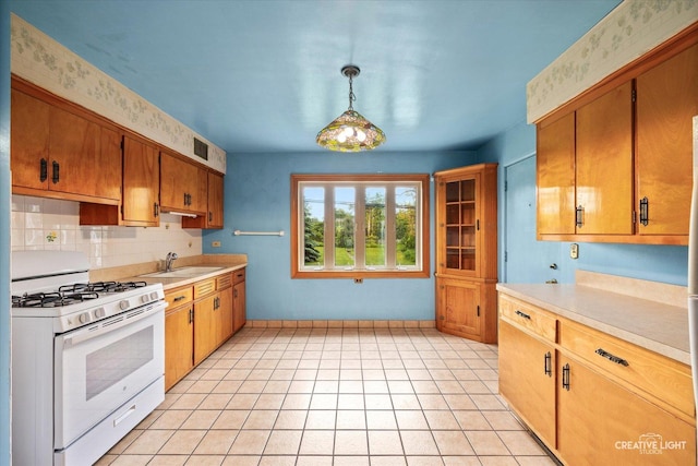 33 Chestnut Ave, Clarendon Hills, IL 60514 - kitchen featuring white range with gas cooktop, a sink, light countertops, brown cabinetry, and tasteful backsplash