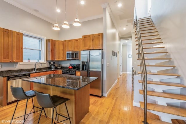 kitchen with a center island, ornamental molding, a sink, a kitchen breakfast bar, and stainless steel appliances
