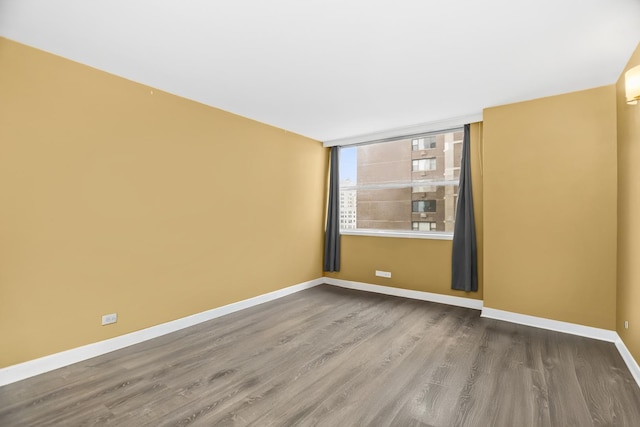 spare room with baseboards and wood finished floors
