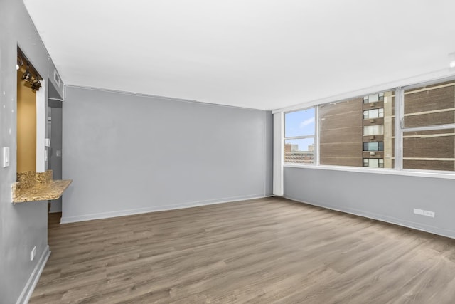 spare room with baseboards and wood finished floors