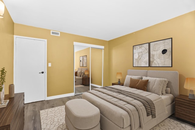 bedroom with baseboards, a closet, wood finished floors, and visible vents