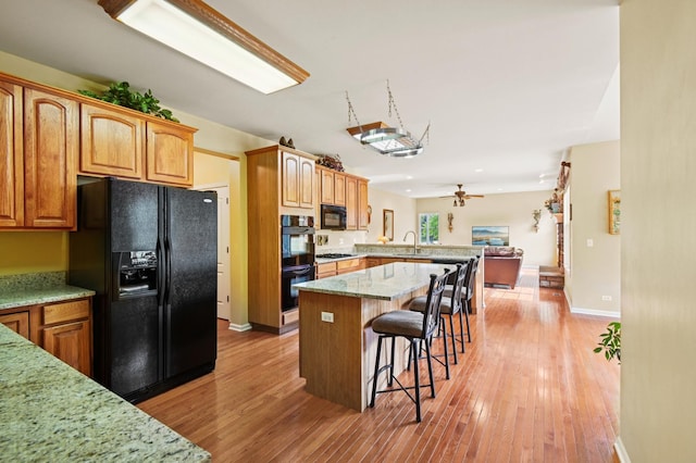 7770 Farrell Dr, Lakewood, IL 60014 - kitchen featuring black appliances, a breakfast bar, ceiling fan, open floor plan, and a peninsula