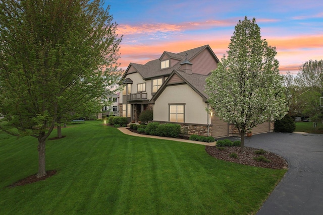 7770 Farrell Dr, Lakewood, IL 60014 - view of front facade with a balcony, stucco siding, stone siding, a lawn, and asphalt driveway