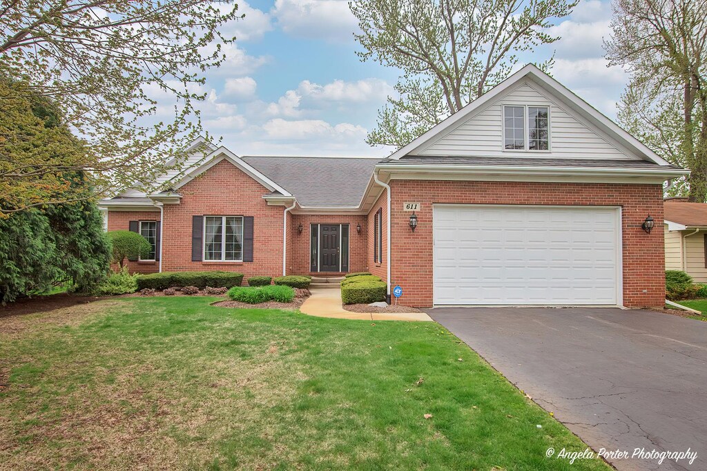 view of front of home featuring a garage, aphalt driveway, a front yard, roof with shingles, and brick siding
