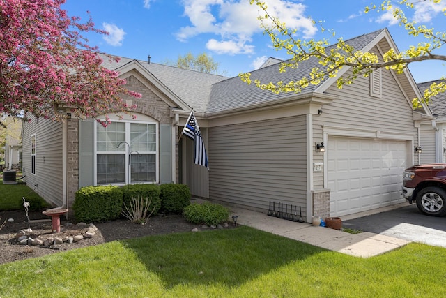 view of front of house featuring roof with shingles, a front yard, a garage, and brick siding