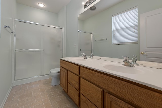 bathroom featuring a stall shower, toilet, double vanity, and baseboards