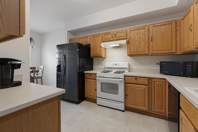 kitchen featuring black appliances, under cabinet range hood, light countertops, and brown cabinets
