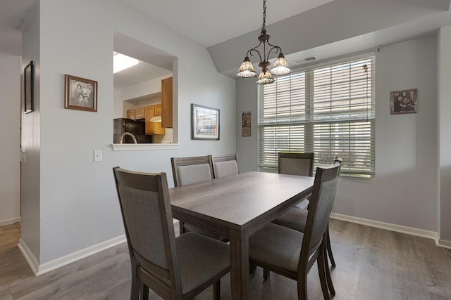 dining area featuring wood finished floors, a chandelier, and baseboards