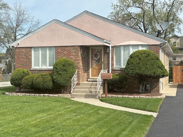 view of front of home featuring stucco siding, brick siding, and a front lawn