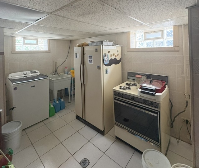kitchen with washer / clothes dryer, light tile patterned flooring, and white appliances
