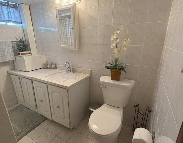 bathroom featuring toilet, tile patterned floors, tile walls, and vanity