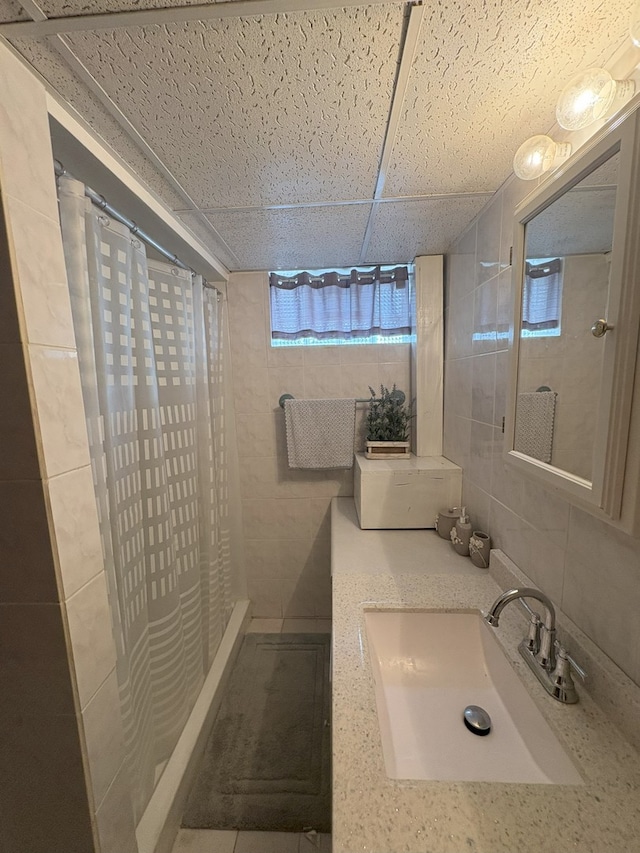 bathroom featuring a sink, backsplash, a drop ceiling, and a shower with shower curtain
