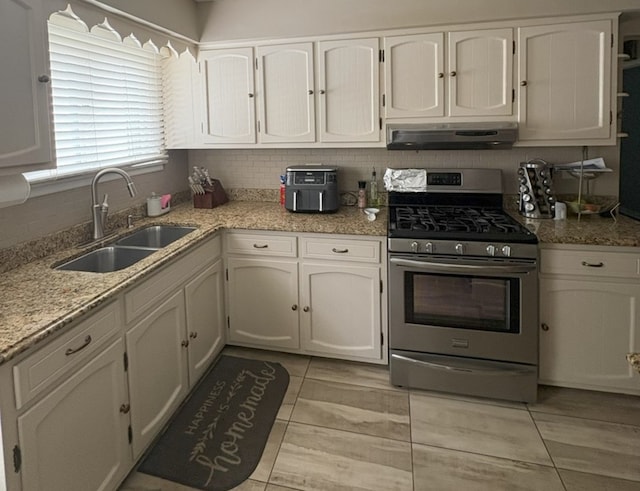 kitchen with a sink, under cabinet range hood, stainless steel range with gas cooktop, and white cabinetry