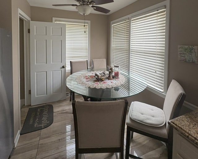 dining area with ceiling fan, baseboards, and light wood finished floors