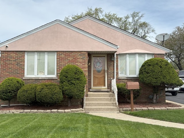 view of front of property with stucco siding, a front lawn, and brick siding