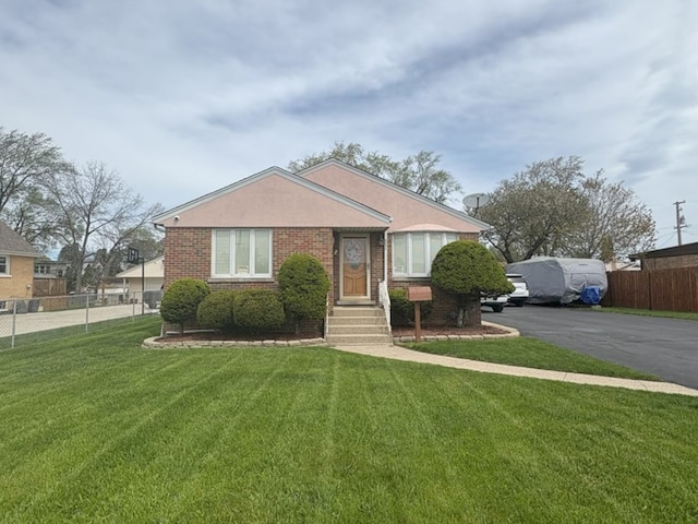 bungalow featuring fence, a front lawn, and brick siding