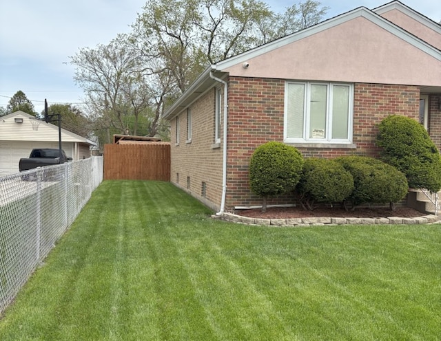 view of side of home with a yard, brick siding, and fence