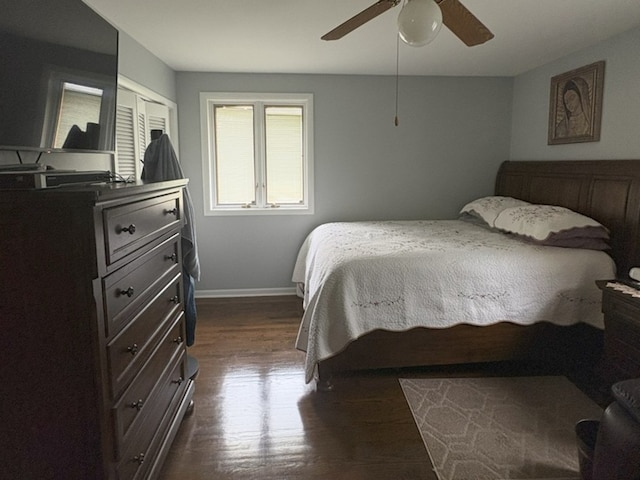 bedroom with baseboards, ceiling fan, a closet, and dark wood-type flooring