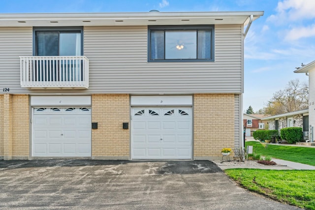 multi unit property featuring a garage, driveway, and brick siding