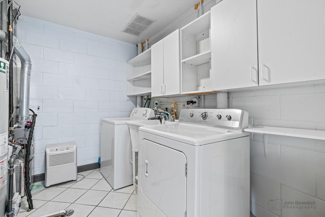 clothes washing area with cabinet space, concrete block wall, light tile patterned floors, visible vents, and washer and clothes dryer