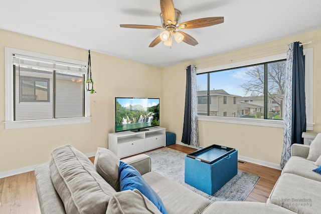 living area featuring a ceiling fan, baseboards, and wood finished floors