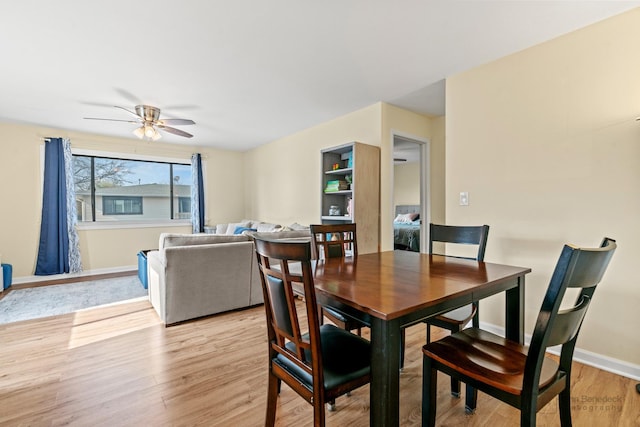 dining area with light wood-style floors, a ceiling fan, and baseboards
