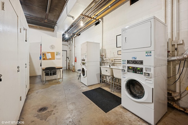 community laundry room with washing machine and clothes dryer, concrete block wall, and stacked washer / drying machine