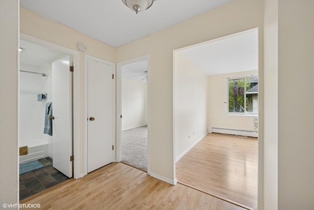corridor with a baseboard radiator and wood finished floors
