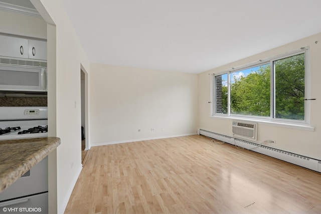 unfurnished living room with a baseboard radiator, an AC wall unit, baseboards, and light wood-type flooring