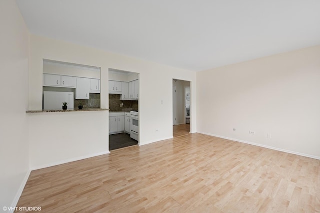 unfurnished living room featuring baseboards and light wood-style floors